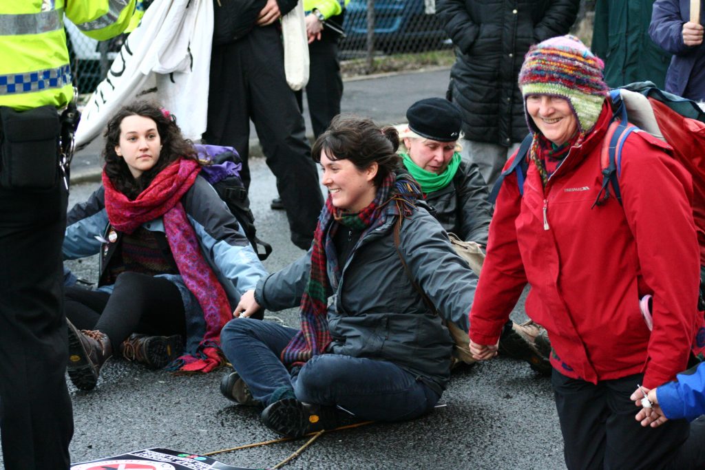 Activists holding hands sitting down on a road